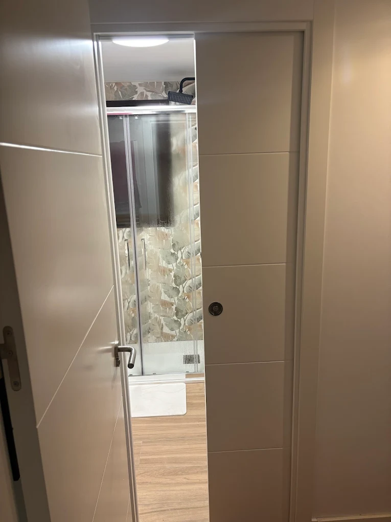 Reforma baño moderno con puerta corredera y ducha efecto tropical Madrid