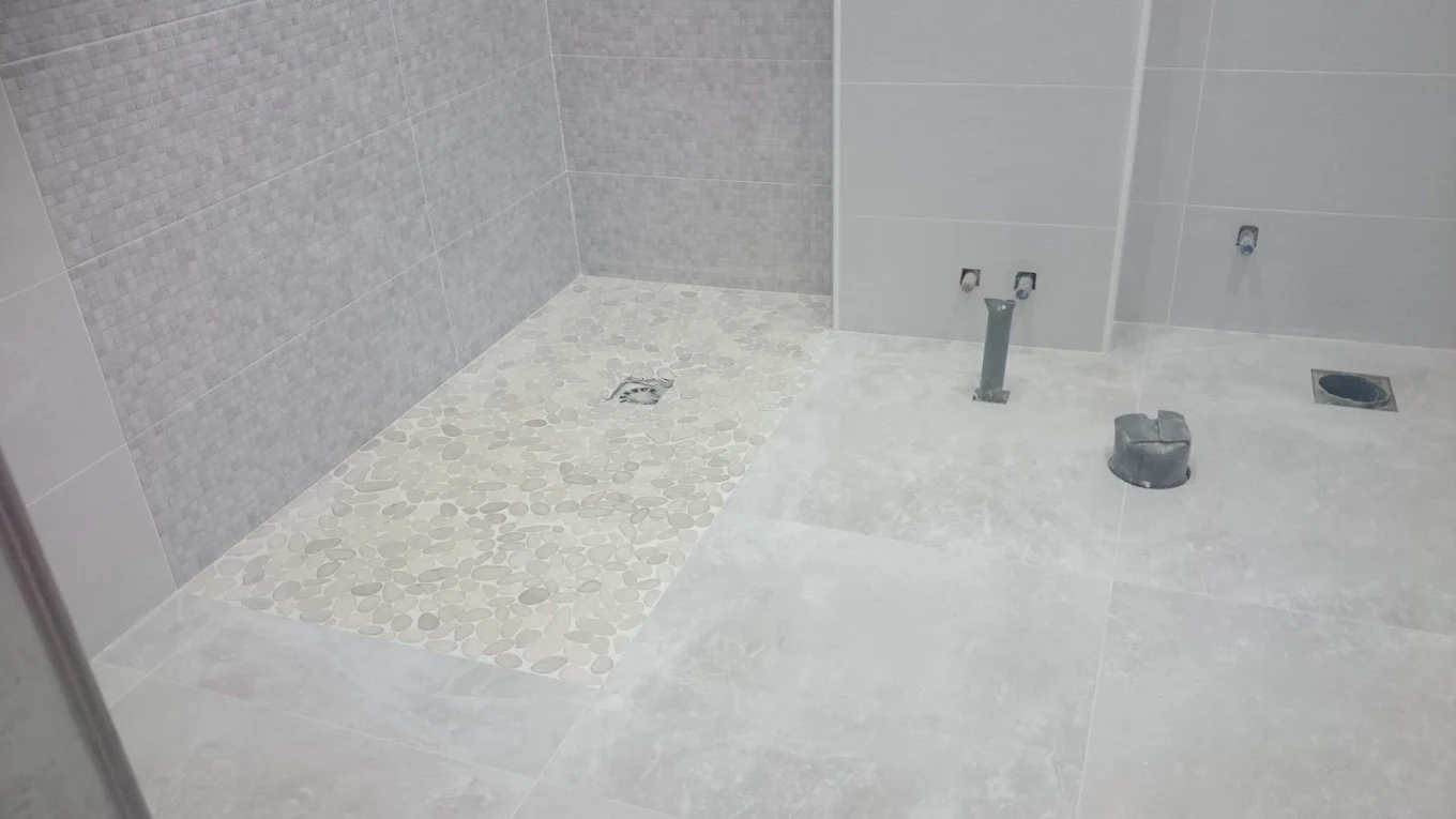 Reforma baño con suelo microcemento y mosaico canto rodado en ducha Madrid