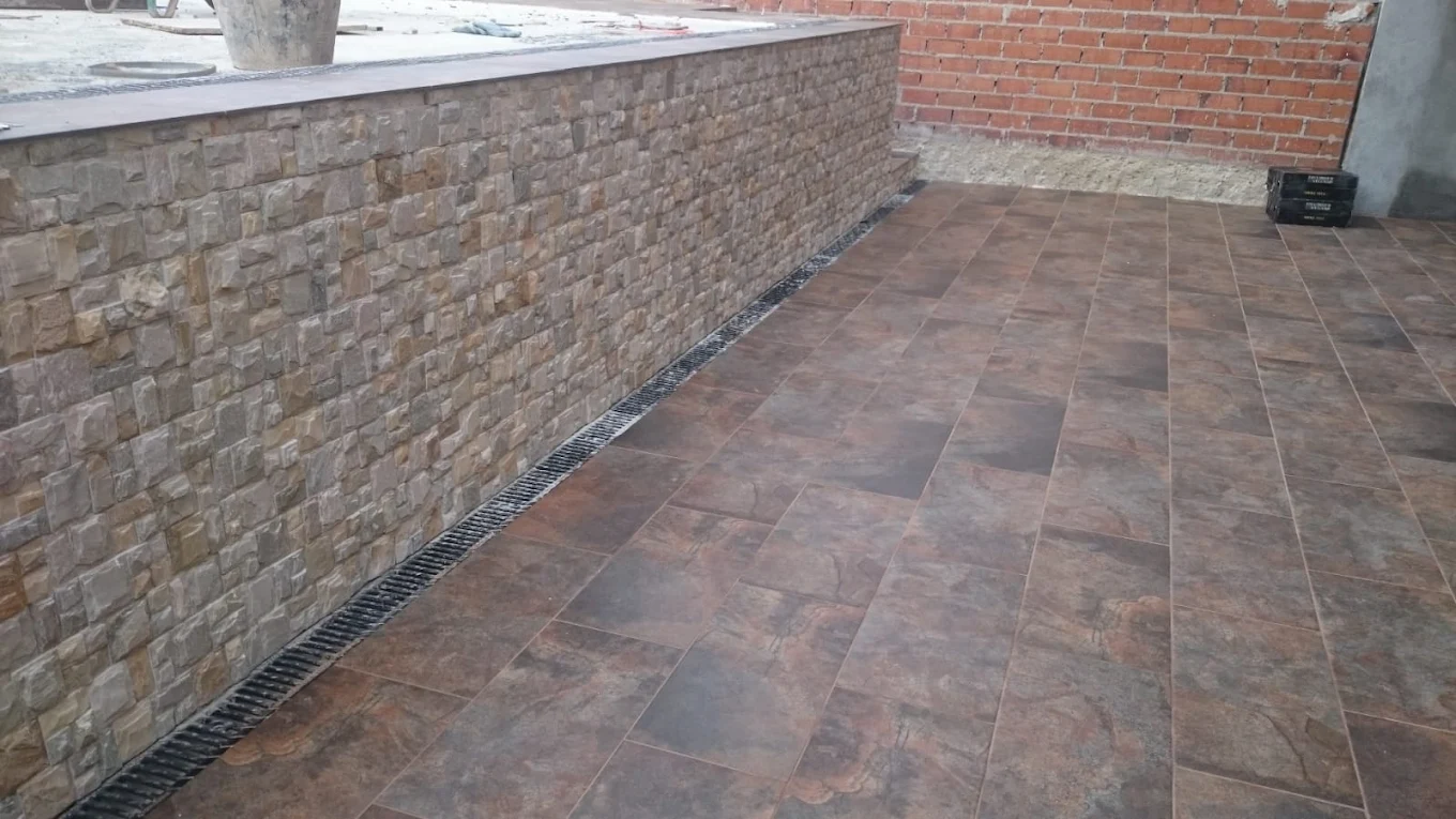 Reforma terraza exterior con solado gres porcelánico y muro piedra natural Madrid